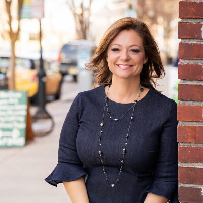 A woman standing beside a brick wall